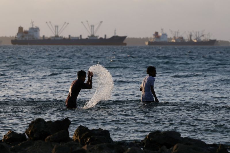 Kids play in the water, as fishing boats pass by, in Majuro lagoon, Marshall Islands, June 17, 2025. REUTERS/Hollie Adams