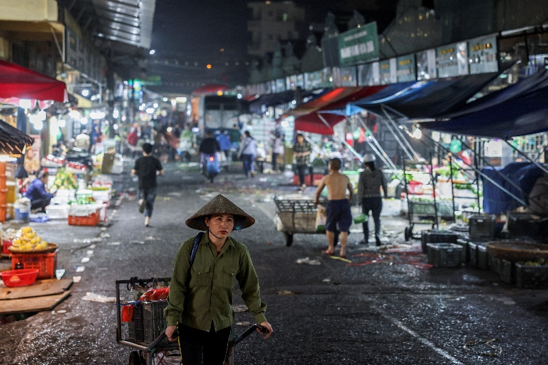 A merchant carries goods that she bought at Long Bien Market, one of the largest wholesale markets in Hanoi, in Hanoi, Vietnam, May 28, 2025. REUTERS/Chalinee Thirasupa