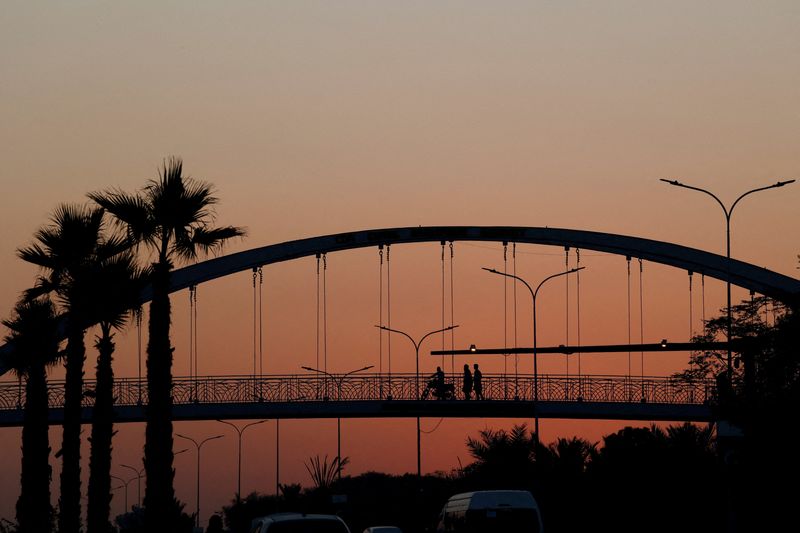 FILE PHOTO: People are silhouetted as they cross a pedestrian bridge during sunset hours, in Islamabad, Pakistan, November 12, 2025. REUTERS/Akhtar Soomro/File Photo