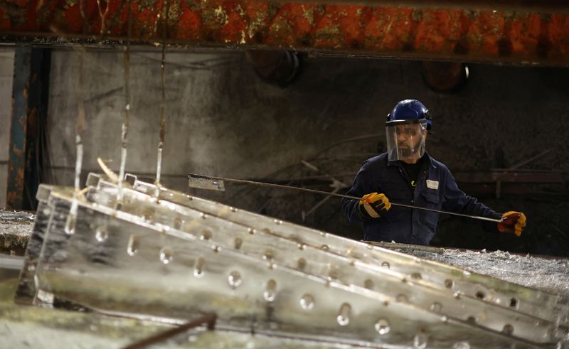 A worker removes pieces of metal from the galvanising bath inside the factory of Corbetts The Galvanizers in Telford, Britain, June 28, 2022. REUTERS/Phil Noble