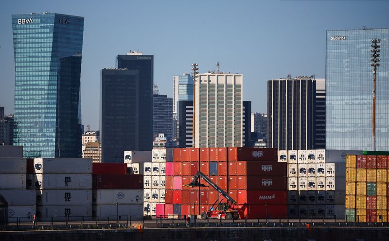 Stacks of shipping containers next to a reach stacker with office buildings in the background, at the port of Buenos Aires, Argentina, January 15, 2026. REUTERS/Agustin Marcarian