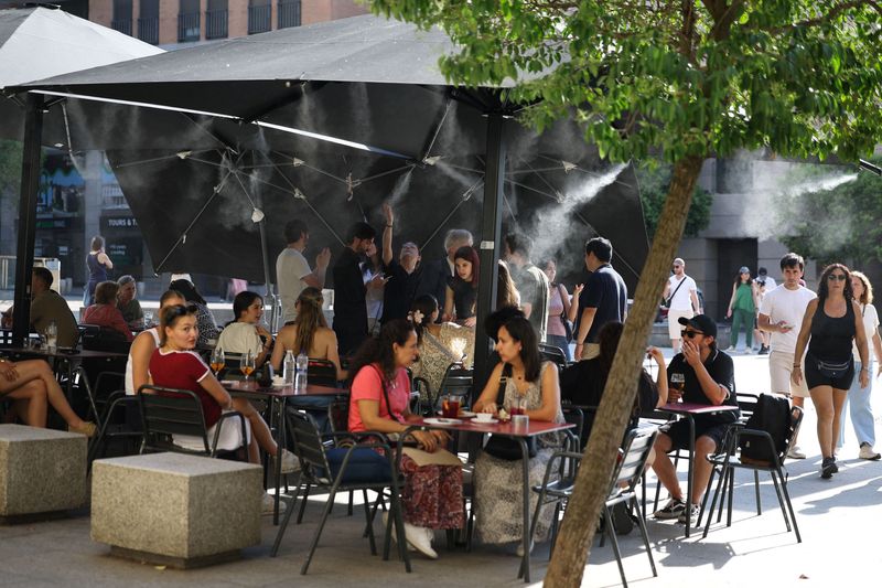 People sit and talk at a bar with mist system to cool clients, during a spring heatwave in Madrid, Spain, May 29, 2026. REUTERS/Kacper Pempel