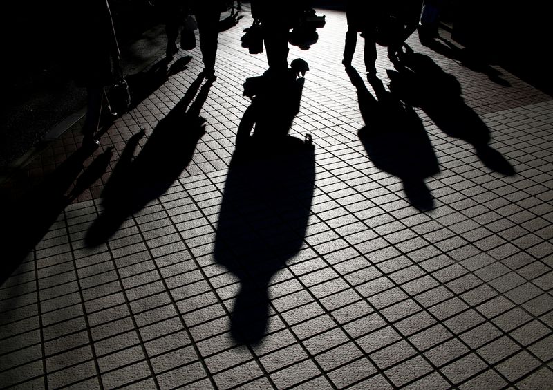 FILE PHOTO: Pedestrians cast shadows as they make their way at a financial district in Tokyo, Japan, January 26, 2017. Picture taken on January 26, 2017.   REUTERS/Kim Kyung-Hoon/File Photo