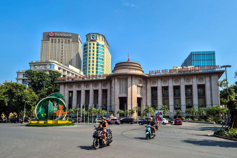 People ride motorcycles in front of the headquarter of the State Bank of Vietnam in Hanoi, Vietnam, November 19, 2024. REUTERS/Khanh Vu