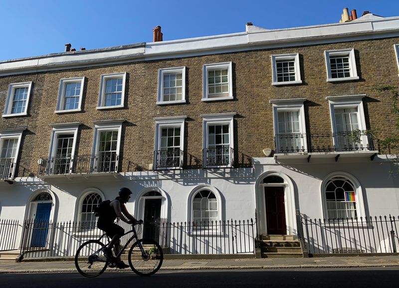 A person on a bicycle rides past houses on a street early in the morning in Islington, London, Britain, June 22, 2020.   REUTERS/Simon Newman