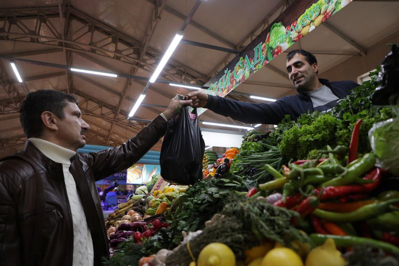 A vendor hands over a bag of vegetables to a customer at a food market in Saint Petersburg, Russia, November 10, 2023. REUTERS/Anton Vaganov