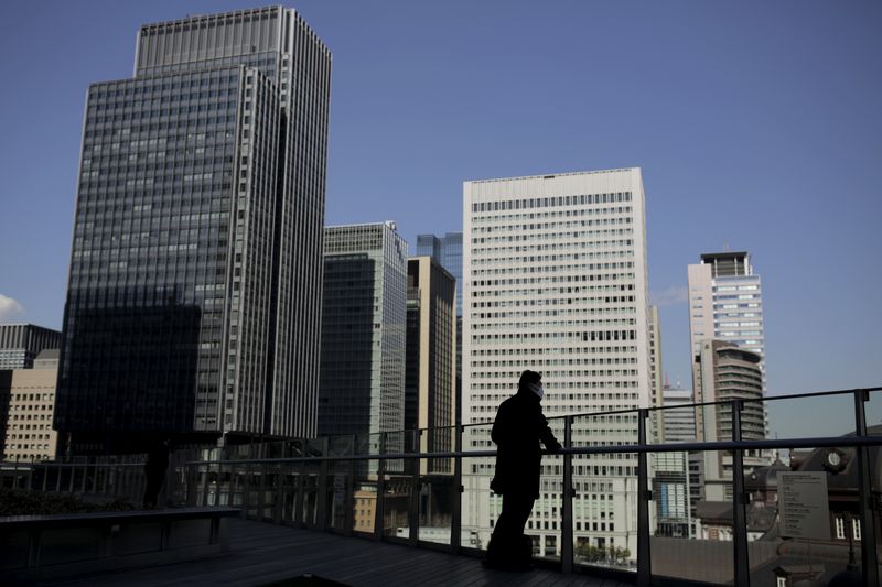 A businessman stands on a terrace overlooking a banking district in Tokyo, Japan, February 16, 2016. REUTERS/Thomas Peter