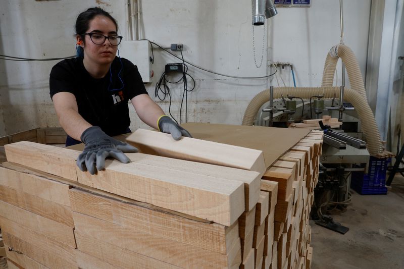 A worker stacks pieces of wood at Hidrau's piano bench factory, in Algemesi, near Valencia, Spain, October 24, 2025. REUTERS/Eva Manez