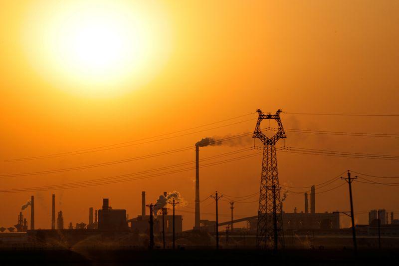 Factories and electricity transmission towers are silhouetted during sunset, in Handan, Hebei province, China April 7, 2026. REUTERS/Tingshu Wang