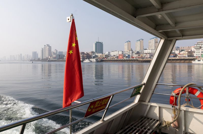 A Chinese flag on a tourist boat travelling on the Yalu river, which separates China and North Korea, near Dandong's waterfront skyline, in Dandong, Liaoning province, China, January 15, 2026. REUTERS/Maxim Shemetov