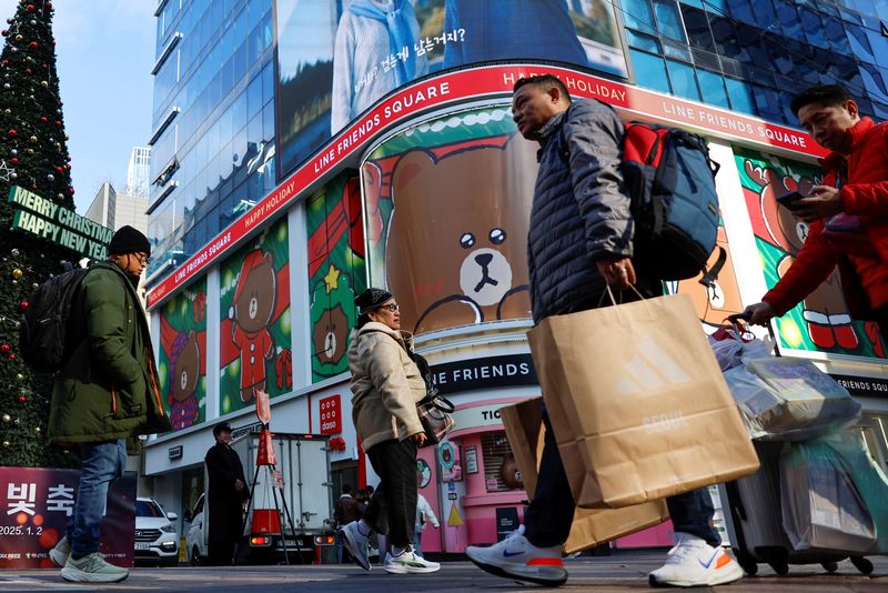 A man holding a shopping bag walks at Myeongdong Street in Seoul, South Korea, December 5, 2024. REUTERS/Kim Soo-hyeon