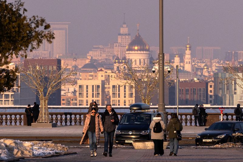 People walk at the Vorobyovy Gory viewpoint with a view of the city's skyline during sunset in Moscow, Russia, February 28, 2025. REUTERS/Maxim Shemetov