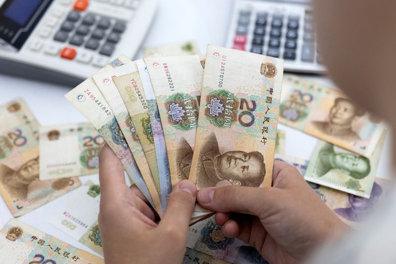 Woman holds Chinese Yuan banknotes in this illustration taken May 30, 2022. REUTERS/Dado Ruvic/Illustration