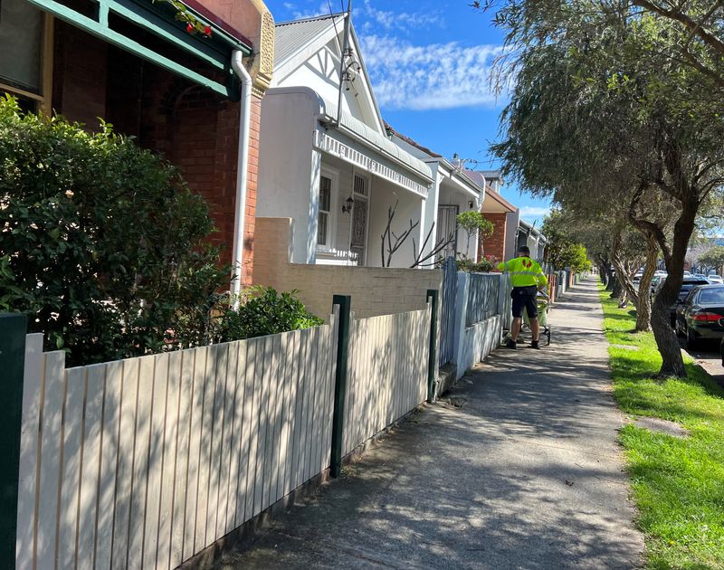 FILE PHOTO: A post office worker delivers mail to townhouses in Leichhardt, Sydney, August 29, 2023. REUTERS/Stella Qiu/File Photo