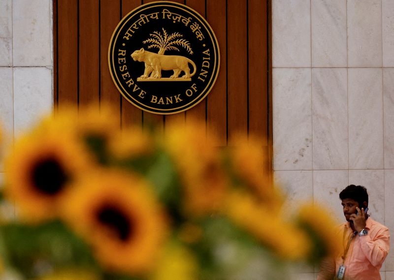 FILE PHOTO: A man speaks on his phone as he walks past the Reserve Bank of India (RBI) logo inside its headquarters in Mumbai, India, February 7, 2025. REUTERS/Francis Mascarenhas/File Photo