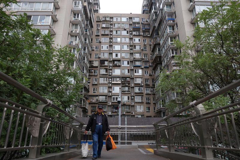 A man walks on a pedestrian bridge near residential buildings in Beijing, China October 17, 2024. REUTERS/Florence Lo