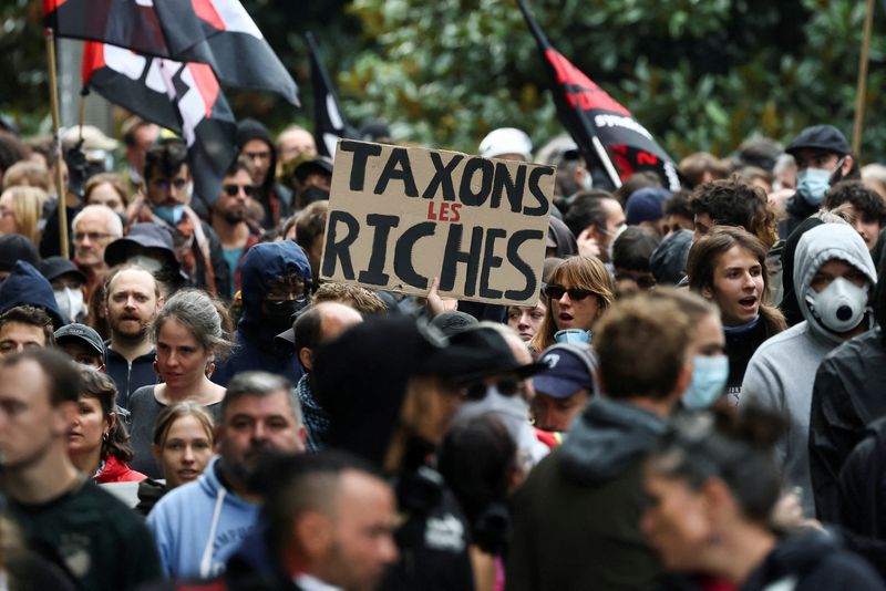 FILE PHOTO: A person holds a placard which reads, "Let's tax the rich" as protesters demonstrate as part of a second day of action by a popular protest movement called "Bloquons Tout" ("Let's Block Everything") calling for nationwide all-day disruptions, and five days before another major day of national mobilisation is expected, in Nantes, France, September 13, 2025.  REUTERS/Stephane Mahe/File Photo