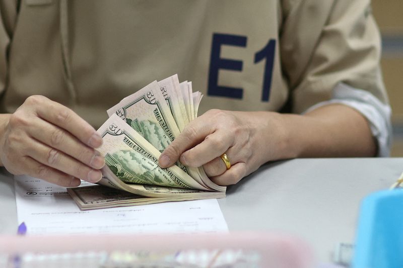 A bank employee counts U.S. dollar notes at a Kasikornbank in Bangkok, Thailand, January 26, 2023. REUTERS/Athit Perawongmetha/File Photo
