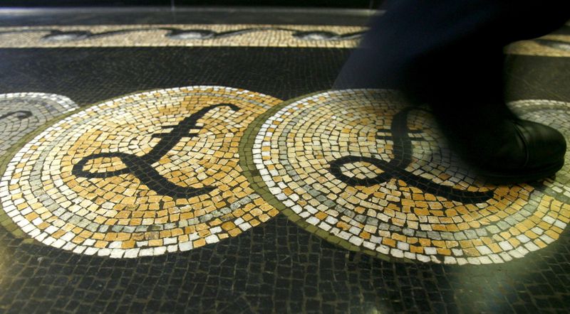 An employee is seen walking over a mosaic of pound sterling symbols set in the floor of the front hall of the Bank of England in London, in this March 25, 2008 file photograph. REUTERS/Luke MacGregor/File Photo