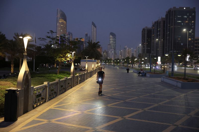 A person rides a scooter with the skyline visible in the background, in Abu Dhabi, United Arab Emirates, September 27, 2023. REUTERS/Amr Alfiky