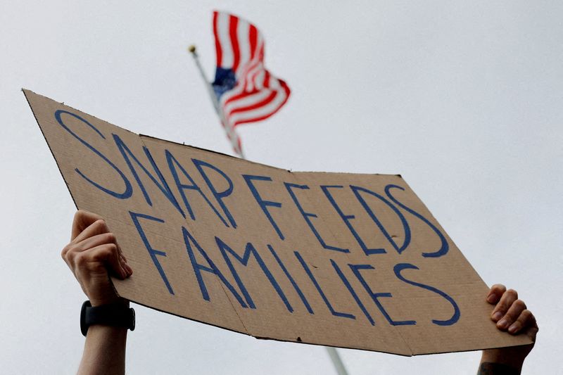 FILE PHOTO: A man holds a sign reading "SNAP Feeds Families," as food aid benefits will be suspended starting November 1 amid the ongoing U.S. government shutdown, during "A Rally for SNAP" on the steps of the Massachusetts Statehouse in Boston, Massachusetts, U.S., October 28, 2025. REUTERS/Brian Snyder/File Photo/File Photo