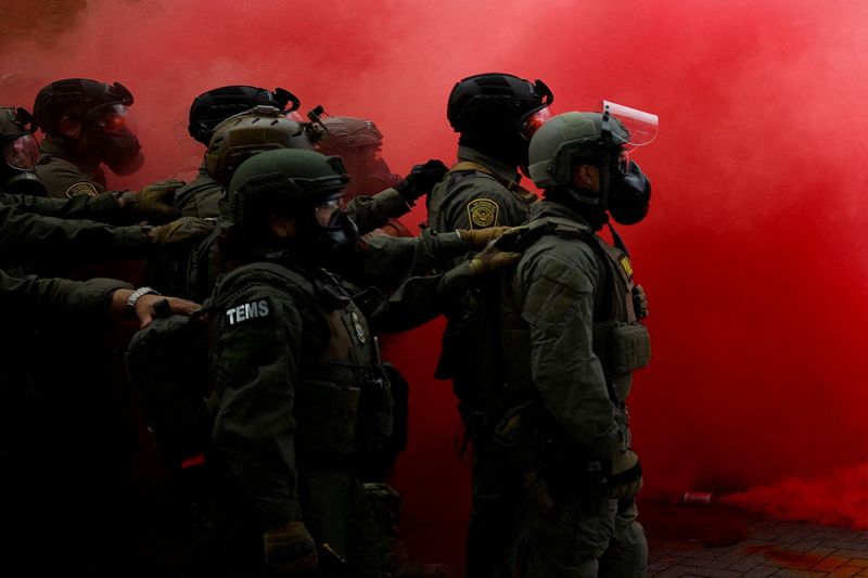 Law enforcement officers stand amid smoke from a smoke grenade released to disperse demonstrators in front of the U.S. Immigration and Customs Enforcement (ICE) headquarters in Portland, Oregon, U.S., October 4, 2025.  REUTERS/Carlos Barria   TPX IMAGES OF THE DAY   Pulitzer Prize Finalist for Breaking News Photography