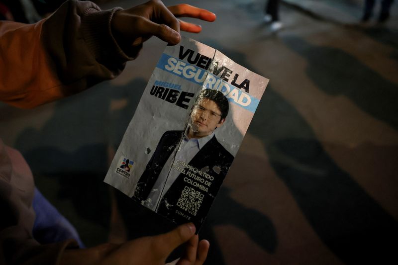 A persin holds a campaign poster at the area where Colombian Senator Miguel Uribe Turbay of the opposition Democratic Center party, was shot during a campaign event, in Bogota, Colombia, June 7, 2025. REUTERS/Luisa Gonzalez