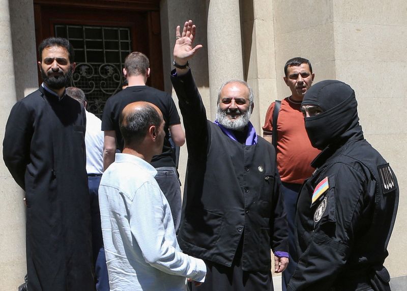 Archbishop of the Armenian Apostolic Church Bagrat Galstanyan, who is charged with attempting to overthrow the government and destabilizing the state, waves to supporters as Armenia's National Security officers arrive to arrest him in Yerevan, Armenia, June 25, 2025. Melik Baghdasaryan/Photolure via REUTERS