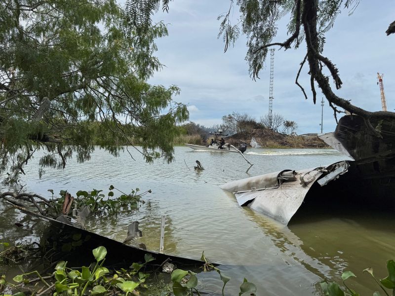 FILE PHOTO: Debris from a SpaceX spacecraft lies partially submerged in the Rio Grande River as a boat navigates nearby, as seen from Matamoros, Mexico, June 19, 2025. REUTERS/Abraham Pineda/File Photo