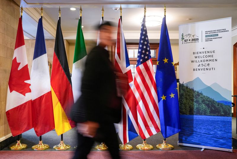 FILE PHOTO: A man walk past the G7 members flags at the Manoir Richelieu before the G7 Foreign Ministers summit in La Malbaie, Quebec, Canada March 12, 2025.  REUTERS/Mathieu Belanger/File Photo