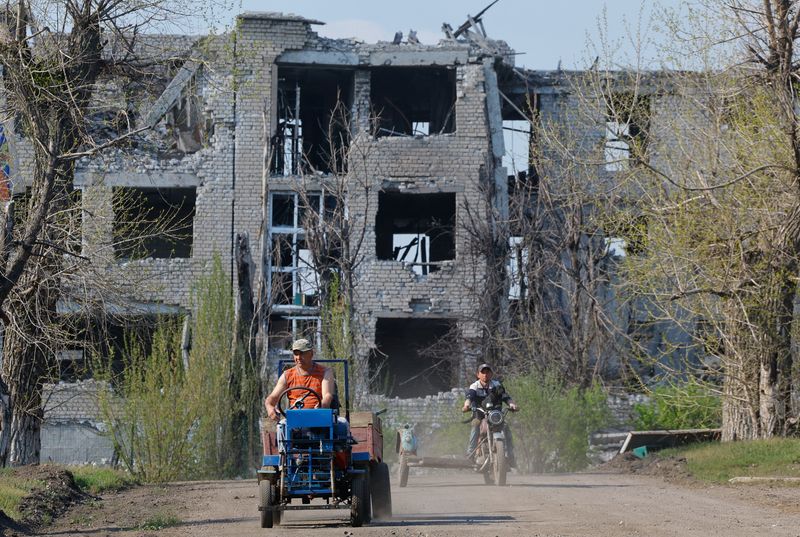 FILE PHOTO: Men ride vehicles near a building destroyed in the course of Russia-Ukraine conflict in Toshkivka (Toshkovka) in the Luhansk region, a Russian-controlled area of Ukraine, April 17, 2025. REUTERS/Alexander Ermochenko/File photo