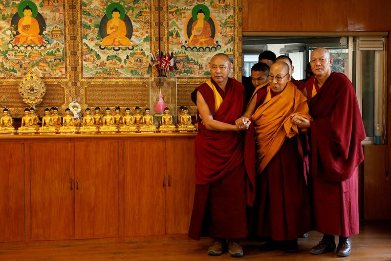 FILE PHOTO: Tibetan spiritual leader, the Dalai Lama, is escorted into a hall by monks holding his hands at his Himalayan residence in Dharamshala, India, December 20, 2024. REUTERS/Priyanshu Singh/File photo
