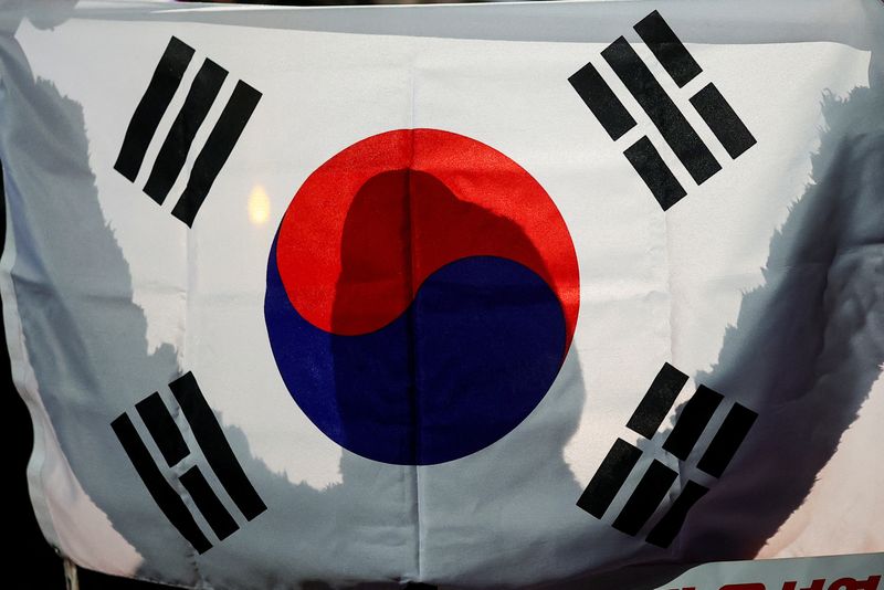 FILE PHOTO: A person holds a South Korean flag in front of the National Assembly in Seoul, South Korea, December 6, 2024. REUTERS/Kim Hong-ji/File photo