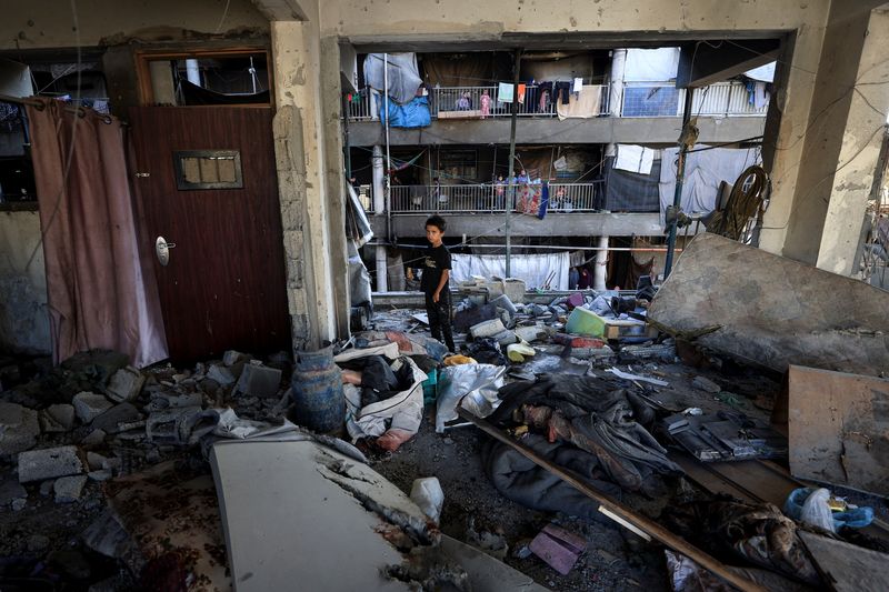 A Palestinian boy inspects the damage at an UNRWA school sheltering displaced people that was hit in an an overnight Israeli strike, in Gaza City, July 5, 2025. REUTERS/Dawoud Abu Alkas