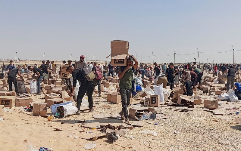 FILE PHOTO: Palestinians collect what remains of relief supplies from the distribution center of the U.S.-backed Gaza Humanitarian Foundation, in Rafah, in the southern Gaza Strip, June 5, 2025. REUTERS/Stringer/File Photo