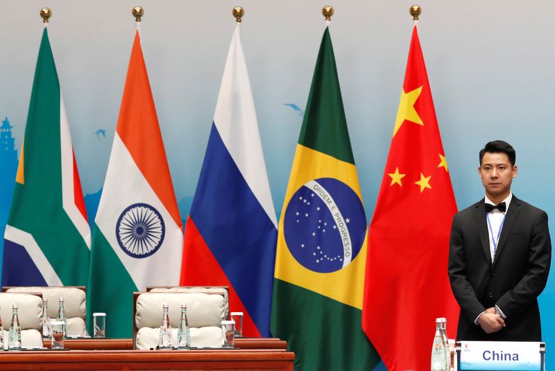 FILE PHOTO: An attendant stands next to South African, Indian, Russian, Brazilian and Chinese flags during a plenary session of BRICS Summit, in Xiamen, China September 4, 2017. REUTERS/Tyrone Siu/File Photo
