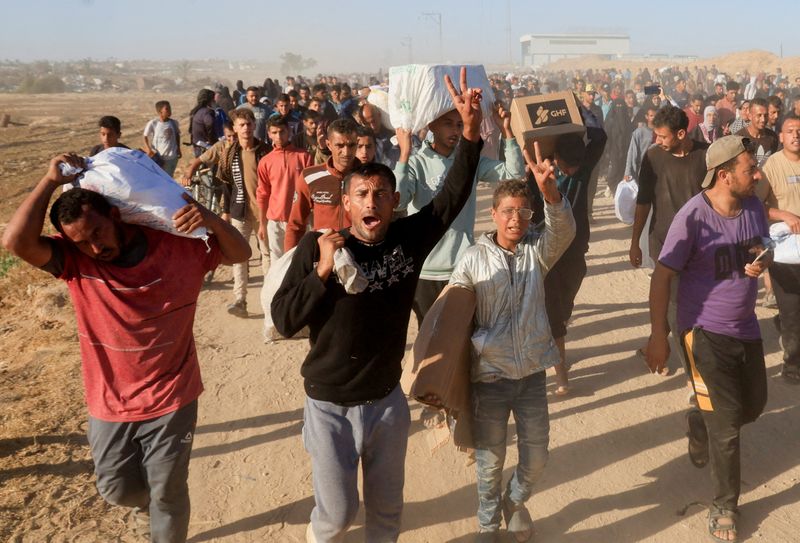 FILE PHOTO: Palestinians carry aid supplies from the U.S.-backed Gaza Humanitarian Foundation, in Khan Younis, in the southern Gaza Strip, May 29, 2025. REUTERS/Hatem Khaled/File Photo