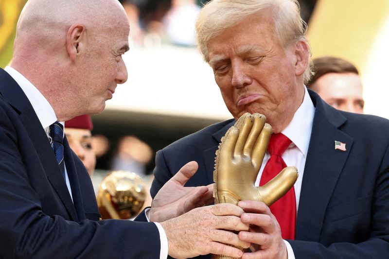 FILE PHOTO: U.S. President Donald Trump looks at the golden glove trophy next to FIFA president Gianni Infantino after Chelsea won against Paris St Germain in the FIFA Club World Cup final, at the MetLife Stadium in East Rutherford, New Jersey, U.S., July 13, 2025. REUTERS/Kevin Lamarque/Pool/File Photo