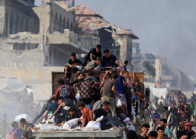 FILE PHOTO: Palestinians ride on a truck as they collect aid supplies that entered Gaza through Israel, in Beit Lahia, in the northern Gaza Strip August 10, 2025. REUTERS/Dawoud Abu Alkas/File Photo