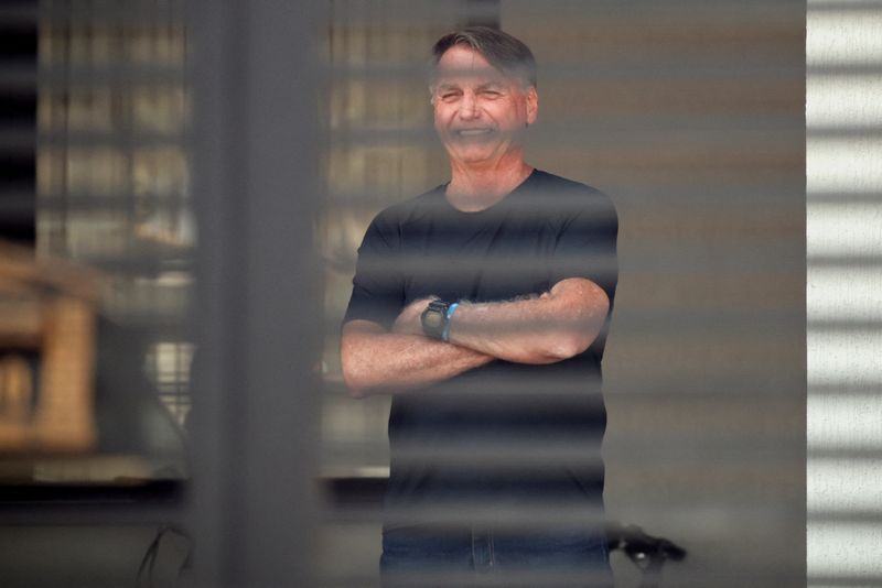 FILE PHOTO: Brazil's former President Jair Bolsonaro stands at his home while under house arrest, ordered by Supreme Court Justice Alexandre de Moraes, as he awaits trial over an alleged plot to overturn the 2022 election, in Brasília, Brazil, August 14, 2025. REUTERS/Adriano Machado/File Photo