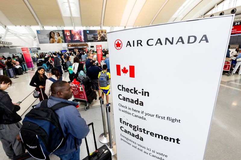 FILE PHOTO: Passengers queue for check-in for their flights at Toronto Pearson International Airport, following the end of the Air Canada labour strike, in Mississauga, Ontario, Canada, August 19, 2025.  REUTERS/Carlos Osorio/File Photo