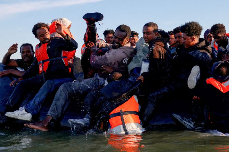 A group of migrants board an inflatable dinghy before leaving the coast of northern France in an attempt to cross the English Channel to reach Britain, from the beach of Petit-Fort-Philippe in Gravelines, near Calais, France, August 25, 2025. REUTERS/Hannah McKay