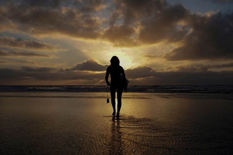 FILE PHOTO: A female surfer walks out into the waves at Cardiff State Beach in Encinitas, California, U.S. October 17, 2019.    REUTERS/Mike Blake/File Photo