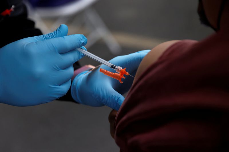 FILE PHOTO: A health care administer gives the second dose of the Pfizer-BioNTech coronavirus disease (COVID-19) vaccine to a person at the L.A. Care Health Plan free testing and vaccination site at the First African Episcopal Church in Los Angeles, California, U.S., January 29, 2022. REUTERS/Shannon Stapleton/File Photo