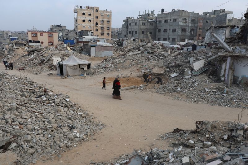 Palestinians walk among piles of rubble and damaged buildings in Khan Younis in the southern Gaza Strip, November 24, 2025. REUTERS/Ramadan Abed