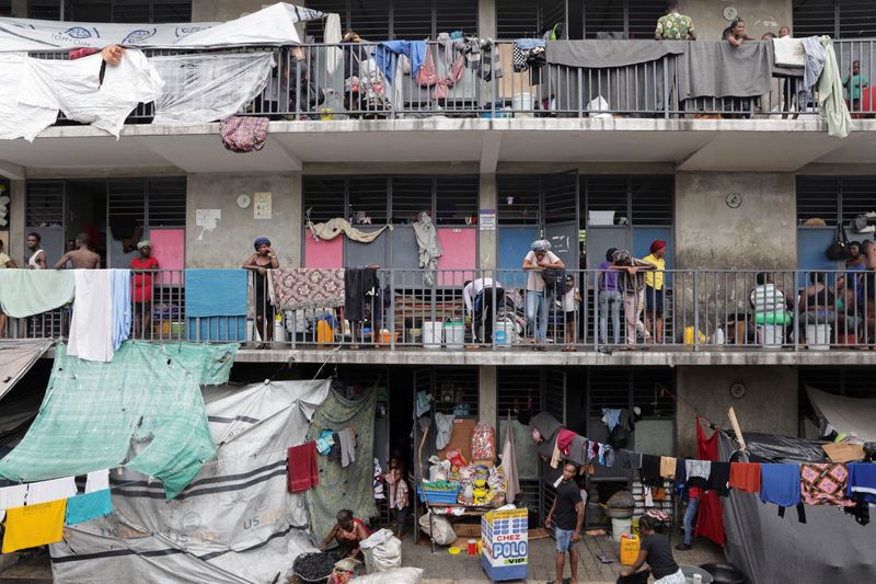 FILE PHOTO: People stand on balconies at the Ecole Nationale Argentine Bellegarde, a school turned into a shelter for some of the more than 1.3 million Haitians who have been internally displaced due to gang violence, in Port-au-Prince, Haiti, October 27, 2025. REUTERS/Patrice Noel/File Photo