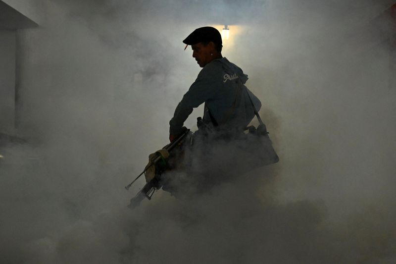 A health worker fumigates a garage with a fogging machine during a public health campaign to prevent mosquito-borne diseases, in Havana, Cuba, November 13, 2025. REUTERS/Norlys Perez