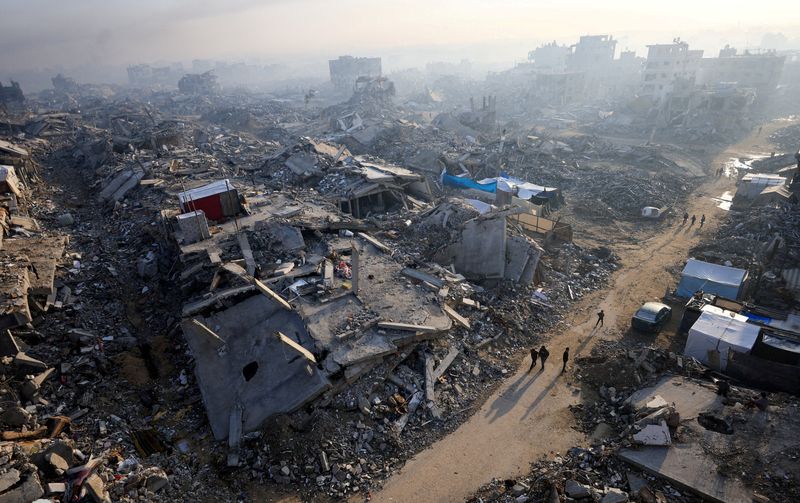 FILE PHOTO: Palestinians walk past the rubble of destroyed buildings, amid a ceasefire between Israel and Hamas, in Gaza City, November 19, 2025. REUTERS/Dawoud Abu Alkas/File Photo