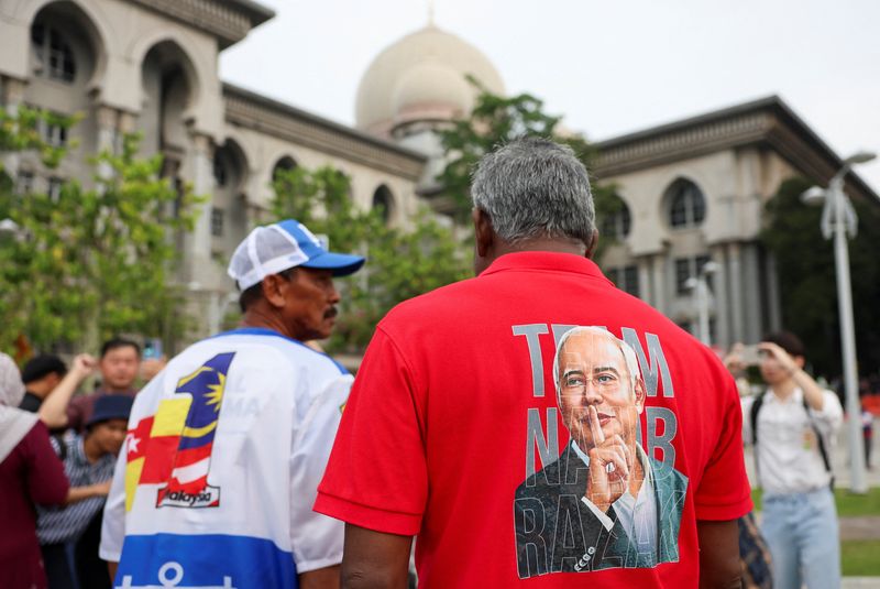 A supporter wears a shirt with former Malaysian Prime Minister Najib Razak's potrait printed on it, outside the Palace of Justice, as the high court will deliver its verdict on four corruption charges and 21 counts of money laundering involving the illegal transfer of about 2.2 billion ringgit ($539 million) from 1Malaysia Development Berhad (1MDB), in Putrajaya, Malaysia December 26, 2025. REUTERS/Hasnoor Hussain
