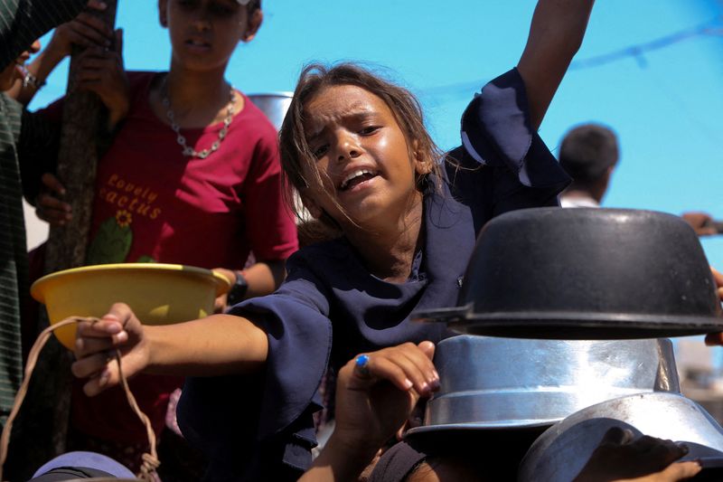 A Palestinian girl gestures as she waits to receive food from a charity kitchen, amid a hunger crisis, in Khan Younis, southern Gaza Strip, August 4, 2025. REUTERS/Hatem Khaled